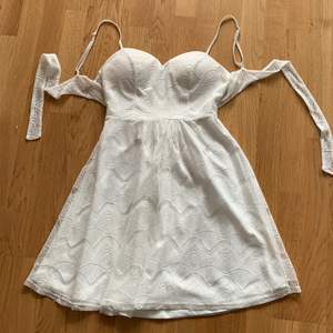En vit kort klänning med mönster som knyter i ryggen från nelly. Den är i storlek 34 men har resår så passar många kroppstyper. Använd 2 gånger.