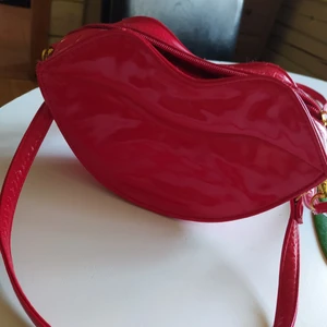 Red lips liten väska nyskick! - Den är i perfekt skick,röd lackad och läcker! Denna sticker garanterat ut ur mängden. Djur och rökfritt hem, samfraktar gärna så kika in mina övriga annonser 🖤