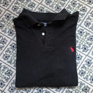 Ralph Lauren pike - Svart pikétröja från Ralph Lauren med rött märke💕 tröjan är i barnstorlek XXL men sitter som en S/M. Köparen står för frakt☺️