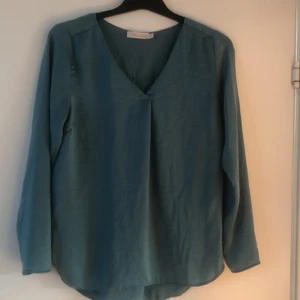 Turkos långärmad blus i silkesmaterial slt 38 - Turkos långärmad blus i silkesmaterial slt 38. Bra skick. V- ringad. 