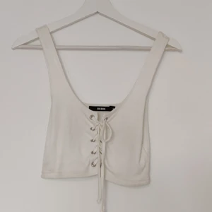 Crop top med snörning - Vit crop top från Bikbok i storlek M. Justerbar snörning framtill. Använd två gånger
