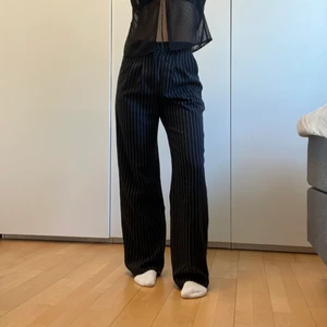 Kostymbyxor Urban Outfitters - Svarta raka/vida kostymbyxor med vita ränder. De är högmidjade och bara använda 2 gånger. Jag är 168 cm för referens. Orginalpris 500kr💓