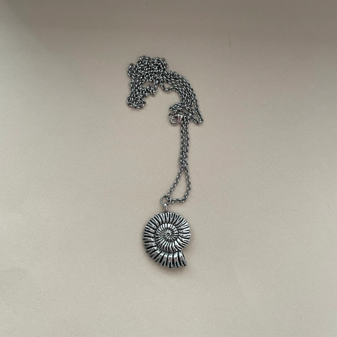 Halsband med silverfärgat fossil-hänge