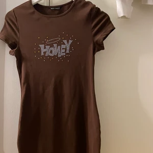 Brun klänning  - Brun klänning ner till knäna från shein med text på bröstet, helt oanvänd 