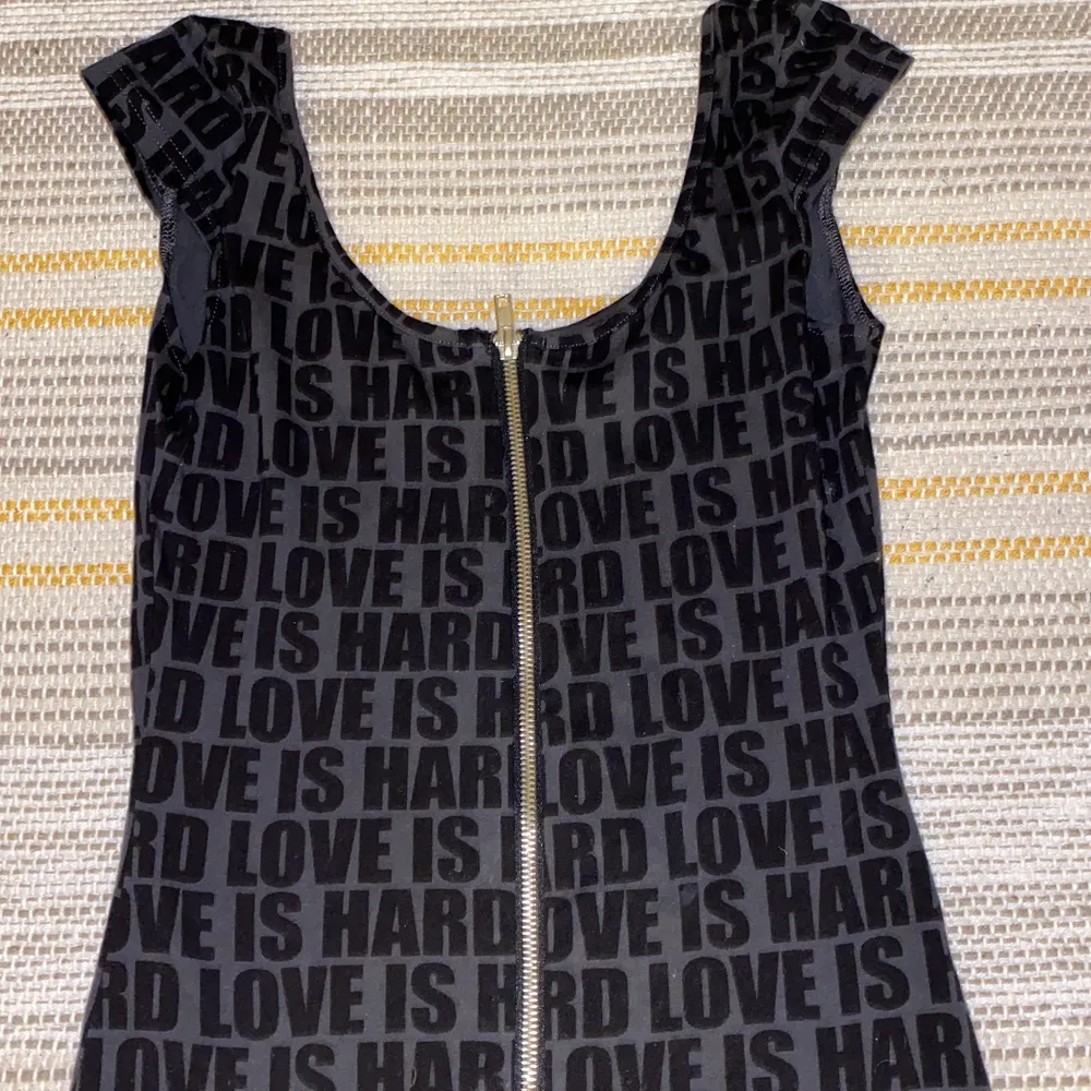Kort svart/mörkgrå klänning med dragkedja framtill och text. Minns ej vart jag köpt denna men aldrig använt.. Klänningar.