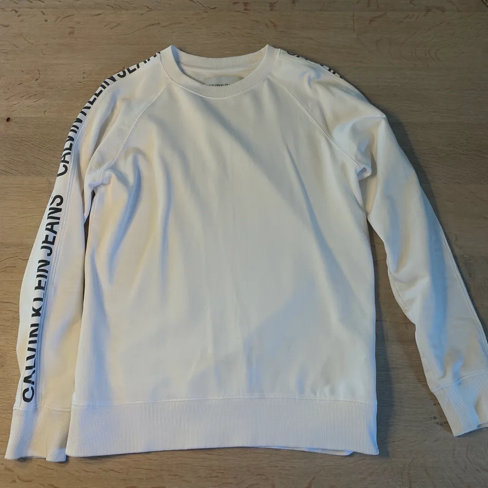 Säljer denna vita Calvin Klein sweatshirten med text på armarna. Vid intresse eller frågor skriv ett meddelande. . Tröjor & Koftor.