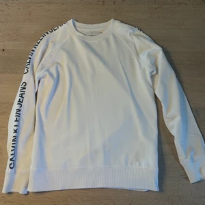 Calvin Klein sweatshirt - Säljer denna vita Calvin Klein sweatshirten med text på armarna. Vid intresse eller frågor skriv ett meddelande. 