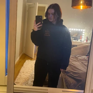 Svart hoodie - Svart hoodie med text fram och på hela ryggen, i storlek S. Oklart vad det står på ryggen. Köpt på secondhand i USA.