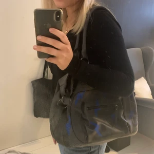 Handväska - Handväska som jag köpt second hand och ritat blåa blixtar på, och en smiley på baksidan. Rymlig och snygg och jag har knappt använt den! 🌟