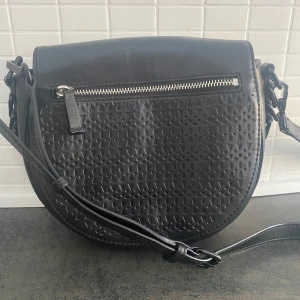 Rebecca Minkoff väska - Rebecca Minkoff sadelbag. Nypris ca 4500kr. Reglerbart axelrem. Lite färg på metall fallit av, men syns ej när man har på sig den. 100% kalvskinn
