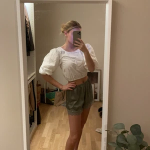 Vit topp  - Vit kort topp med puffiga ärmar och söta detaljer på ryggen. Fint skick, använd endast 2-3 gånger.