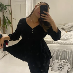 Blus - Svart blus med ”kjol” och fin uringing med knappar 