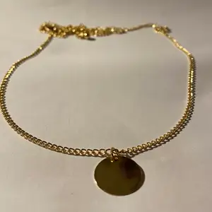 Silverhalsband med gulddetaljer i form av en cirkel.