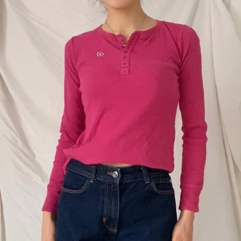 En tröja i pop-rosa färg med ett silvrigt snirkligt broderat B på bröstet. Knappar som går att knäppa eller ha lösa. Använd men bra skick. . Tröjor & Koftor.