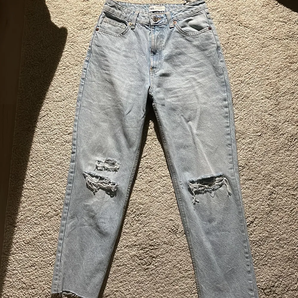 Zara mom jeans med hål i, nya och oanvända. De är i storlek 36 och de är klippta nertill. Jättefina jeans men tyvärr så kommer de inte till användning🤎 (skriv för mer bilder privat). Jeans & Byxor.