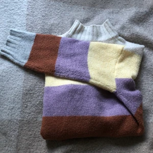 Randig stickad  - Jättefin randig stickad tröja från Gina i lila, gul, vit, brun och grå. Inte perfekt skick, därav priset! Finns ett litet ”hål” vid kragen, skriv för bild