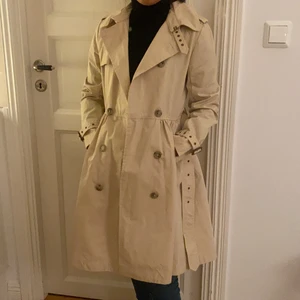 Ralph Lauren Trenchcoat  - Strl 16 (som en xs) Nypris ca 2000. Använd enstaka tillfällen. Nyskick. Beige. Frakt betalar köparen. För varje nytt bud minst 50 kr ökning