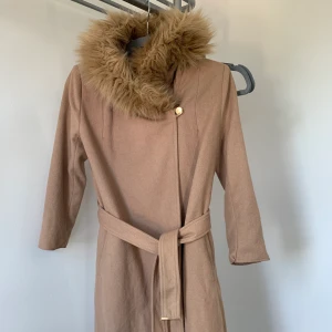 Chiara Forthi Kappa - Kappa ifrån märket chiara forthi i strl 36. Kappan är i fint skick och har guldiga detaljer. Pälsen är inte äkta. Armarna är något korta skulle därför säga att den passar till personer under 160cm