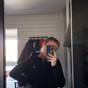 Svart Ralph lauren hoddie med dragkedja  - Jättefin hoddie med dragkedja från Ralph lauren. Köpt i USA på en outlet så den är äkta. Inte använd mycket och därför så säljer den. Nypris 1000 kr, mitt pris 200 kr
