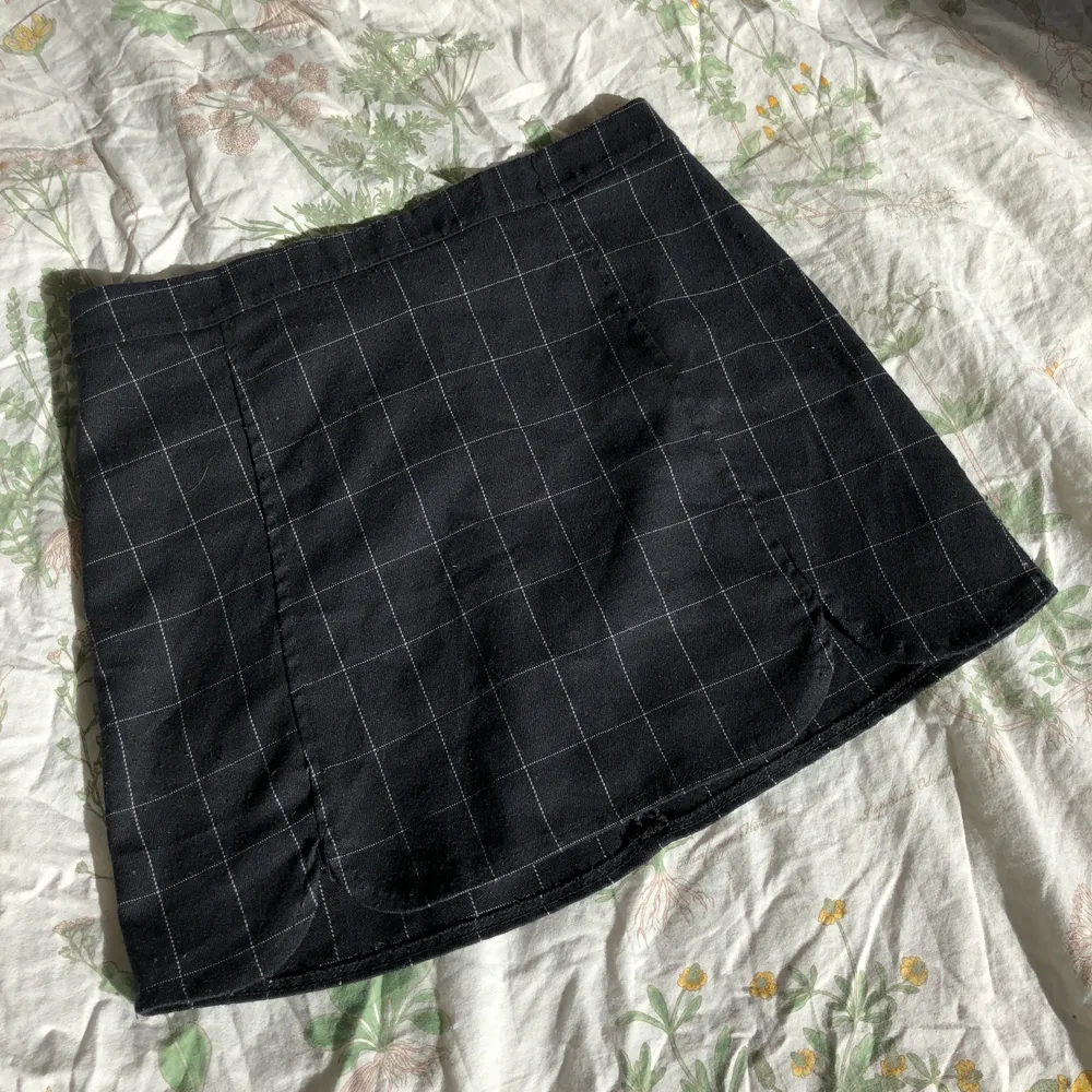 Svart minikjol från Brandy Melville med rutigt/grid mönster i vitt. Två små ”slits” där framme som syns på bild tre. Onesize/stretchig men jag skulle säga att den passar typ xs-medium. Bra skick, inga defekter. . Kjolar.