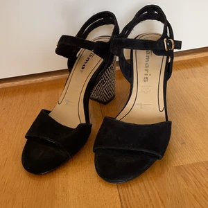 Svarta högklackade sommarskor - Fina skor från Tamaris i storlek 36, säljes då jag flyttar och dom tyvärr inte kommit till användning. Använda två gånger och utan slitningar. Superbekväma trots den relativt höga klacken på ca 8,5 cm. Köparen står för frakten, kan även mötas upp ☺️