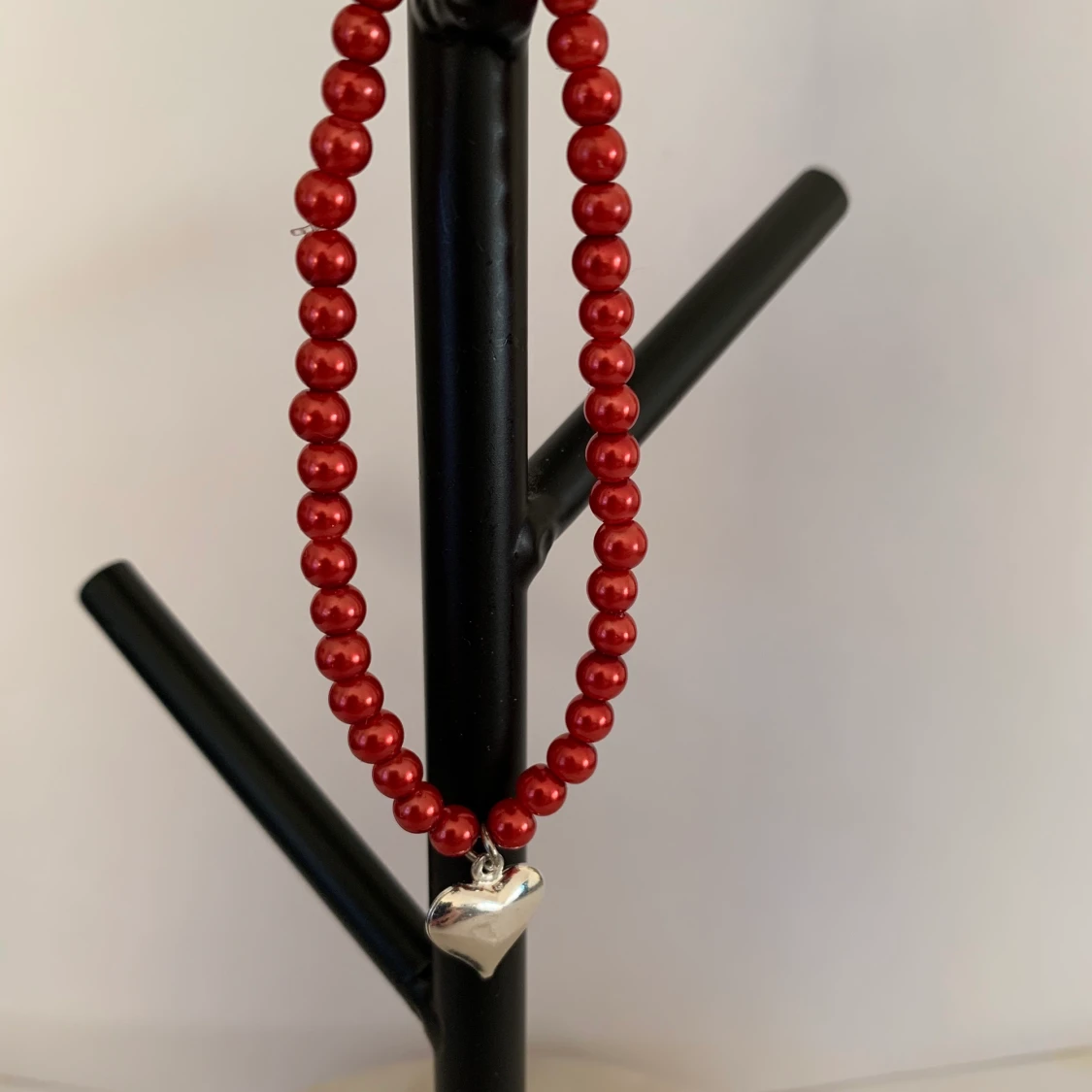 Rött pärlarmband med silvrig hjärtberlock