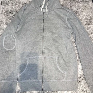 grå huvtröja strlk: S-M - En grå huvtröja med dragkedja. Med cirklar på armbågarna. Löparen fungerar men har tappat lite av delen man håller i när man öppnar och stänger dragkedjan. 