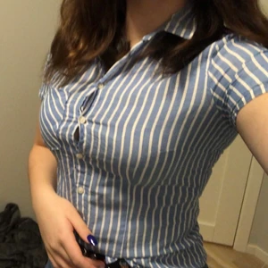 Kortärmad skjorta stl 34 - Blårandig skjorta, kortärmad. Väl använd men i mycket fint skick. Sann i storlek. Inte så lång men inte för kort