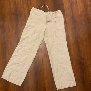 Lågmidjade linnebyxor - Lågmidjade beigea linnebyxor med stora fickor på framsidan och snörning.