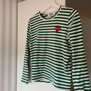 En långärmad t shirt från Comme des Garçons play i storlek M, men sitter mer som en S. Grön och vit randig. Knappt använd så i riktigt bra skick! 