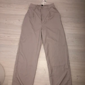 Byxor från h&m - Ett par vida kostymbyxor, lite pösigare kostymbyxor, i färgen beige/grå. Aldrig använda! Storlek 36, jätte fina byxor, säljer pga jag har ett par snarlika 