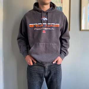 NFL Hoodie - NFL Broncos Football Hoodie i mörkgrå färg! Riktigt bra i passform för dom som brukar bära L. Modellen är 183 cm lång! Tveka inte på att skriva🧡