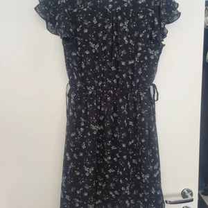 Oanvänd Svart blommig klänning HM - Knytband på sidorna.