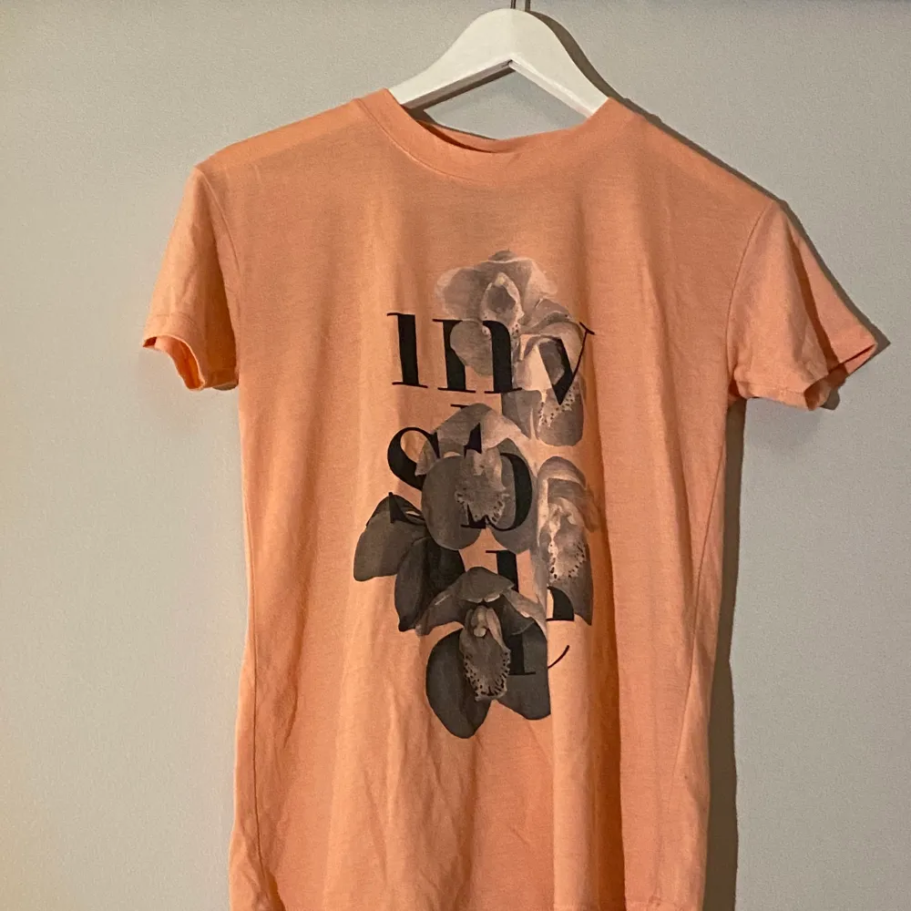 En orange t-shirt med tryck, storlek xs.. T-shirts.