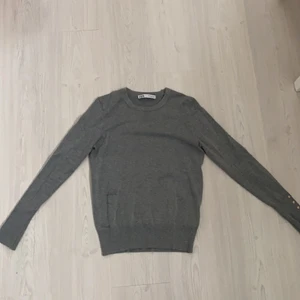 Stickad tröja - En väldigt finstickad grå tröja med guldknappar på armarna (som inte går att öppna) väldigt fint och skönt material som är väldigt mjukt och strechigt, knappt använd. Väldigt fint skick