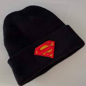 Cool Superman-mössa i svart i jättefint skick. Vuxenstorlek, one size. Frakt tillkommer med 24:-