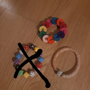 Färglada armband - Söta och färglada armband! ♡ 15 kr styck, knapp armbandet och det beiga armbandet är i mycket bra skick, men den med tärningarna är i sämre skick. Kan mötas upp i centrala Stockholm, eller leverans 24 kr, endast swish <3