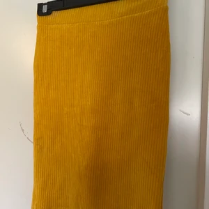 Kjol - Knälång, gul kjol med Manchester mönster. Stretchig och med resår i midjan. Knappt använd 