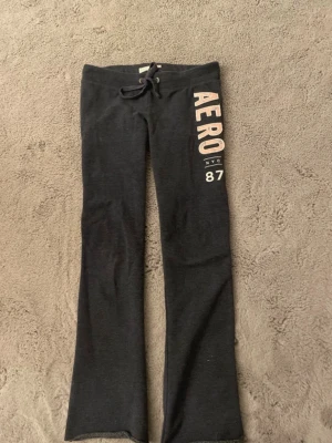 lågmidjade mjukisbyxor - Marinblå v mjukisbyxor från Aeropostale med bred resår och snörning i midjan. Tryck i vitt och rosa med texten 'AERO NYC 87' längs ena benet. Byxorna har raka ben och är gjorda i mjukt, stretchigt material som är riktigt skönt. Passar 153cm-160cm 