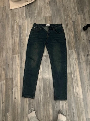 Mörkblå jeans från Stone Island - Säljer ett par mörkblå jeans från Stone Island med klassisk femficksmodell och rak passform. Jeansen har en snygg tvätt med lätt slitning och den ikoniska Stone Island-loggan på bakfickan. Perfekta för dig som gillar streetwear och vill ha något stilrent.