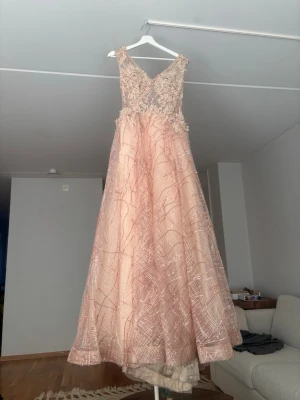 Lång ljusrosa bal-klänning - Elegant långklänning i rosa färg med v-ringad överdel och broderade spetsdetaljer. Kjolen är vid och har ett glittrigt mönster i tyget. Perfekt för bal eller festliga tillfällen. Klänningen är något otroligt, fick väldigt många komplimanger för den. Vid den nedre&inre delen är den lite smutisig men det kan man tvätta bort. Annars är den helt perfekt!!!😍 storleken är 34/36, Xs/S. Vid snabb affär kan priset diskuteras eventuellt sänkas. Men denna klänning är DRÖÖÖMMMM😍😍❤️❤️