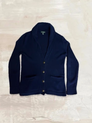 Blå cardigan från Ralph Lauren  - Riktigt snygg cardigan från Ralph lauren. Den är taggad som M men sitter som S. Enda defekten är att en knapp saknas, men märks inte av vid användning. Kom gärna med frågor 😊