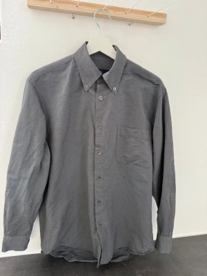 Grå långärmad skjorta i bomull från Zegna - Klassisk grå skjorta med lång ärm och bröstficka. Skjortan har knappar hela vägen fram och button-down krage. Tillverkad i mjuk bomull som känns skön mot huden. Perfekt till jeans eller chinos för en clean look.