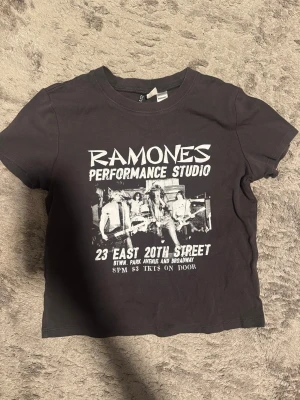 Mörkgrå Ramones t-shirt från H&M Divided - Cool svart t-shirt från H&M Divided med Ramones Performance Studio-tryck i vitt framtill. Klassisk rund hals och korta ärmar. Perfekt för dig som gillar bandtröjor och vill ha en avslappnad stil.