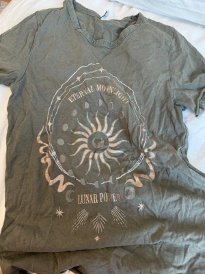 Grön vintage t-shirt med tryck från ONLY - Cool grön t-shirt från ONLY med trycket 'ETERNAL MOONLIGHT LUNAR POWER' och ett sol- och månmotiv framtill. T-shirten har korta ärmar, rund halsringning och är gjord i mjuk bomull. Perfekt för dig som gillar unika prints och avslappnad stil.