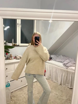 Beige oversized stickad tröja - Mysig beige stickad tröja med oversized passform och långa ärmar. Tröjan har rund halsringning och är tillverkad i ett mjukt, fluffigt material som ger en avslappnad look. Perfekt för lager-på-lager-stil under kyliga dagar.