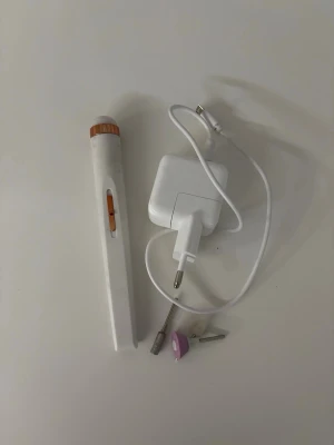 Elektrisk nagelfil med tillbehör - Elektrisk nagelfil i vitt med trädetalj, laddare och tre olika sliphuvuden. Perfekt för att fila, forma och polera naglar hemma. Smidig design som är enkel att använda och ta med sig. Passar både naturliga och konstgjorda naglar.