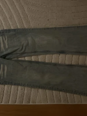 Ljusblåa low waist bootcut jeans med vita detaljer - Säljer ett par ljusblå low waist cheap monday  jeans med bootcut passform och klassisk femficksdesign. Jeansen har en tvättad look och är tillverkade i denim.  Perfekta för dig som gillar en snygg cool outfit💖Andvända få gånger!! strl 23/30