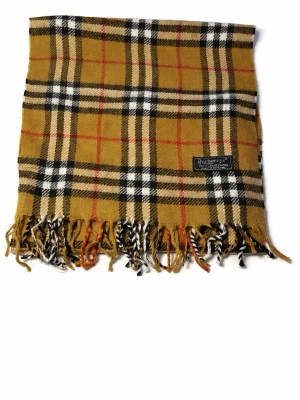 Klassisk beige rutig halsduk Burberry - Snygg beige halsduk från Burberry med ikoniskt rutmönster i svart, vitt och rött. Tillverkad i 100% lammull och har fransar i ändarna. Perfekt accessoar för att lyfta din outfit med en tidlös brittisk touch.