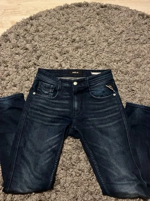 Mörkblå slim fit jeans Replay - Snygga mörkblå jeans från Replay i modellen Anbass med slim fit passform. Jeansen har klassisk femficksdesign, silverfärgade nitar och dragkedja. Materialet är denim med lätt tvättade detaljer för en modern look.